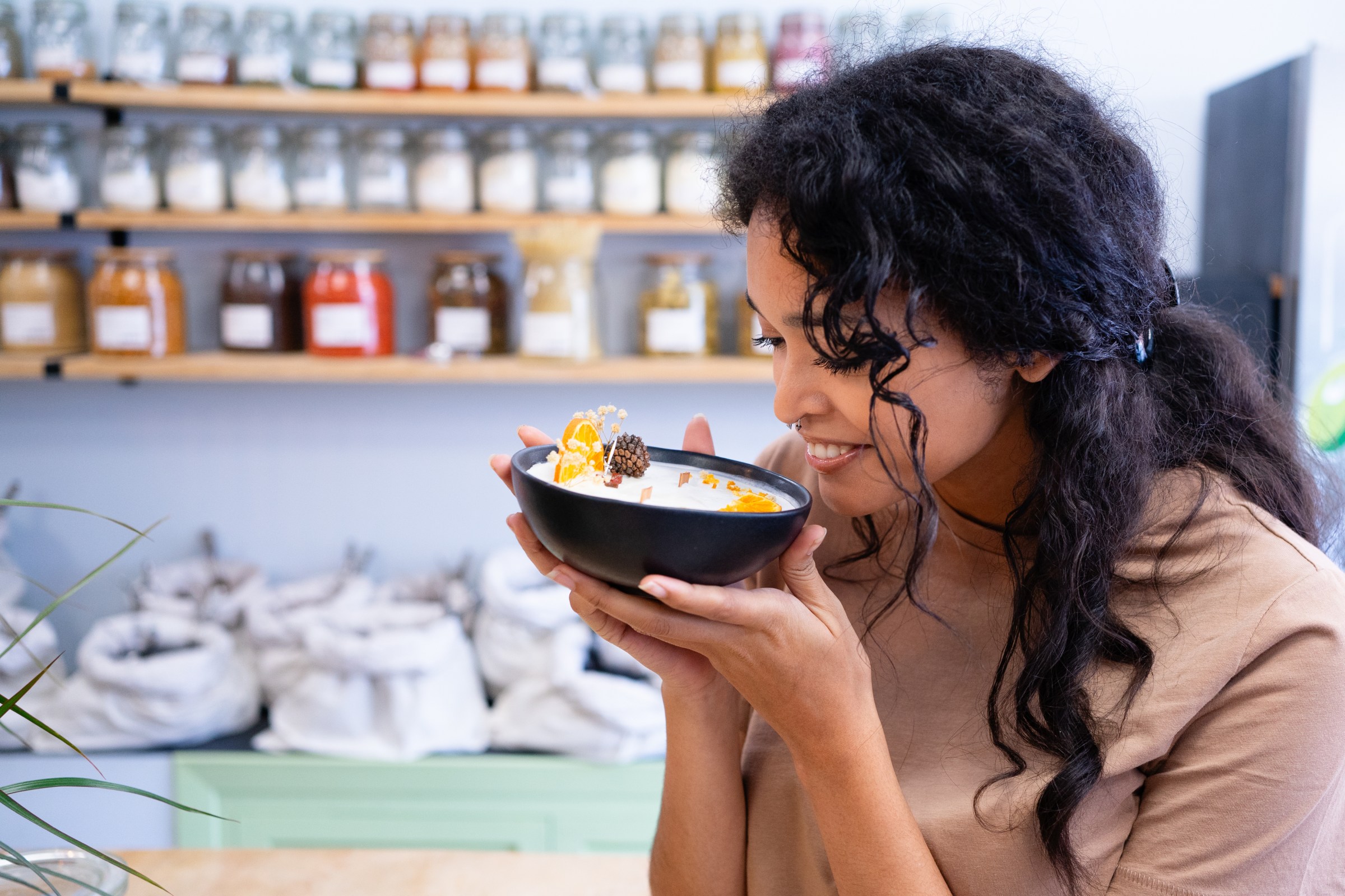 Young woman smelling a scented candle made with natural ingredients at a candle-making event in New York.